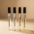 Four perfume bottles with black caps on a beige background